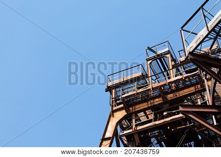 Old rusty metal structures of an abandoned factory against the sky.