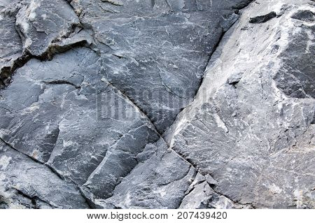 Uneven surface of gray monolithic stone with cracks