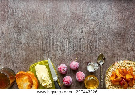 Oatmeal with plums, toast with butter and honey on a wooden table. A cup of black tea. The concept of a healthy breakfast. Top view. Copy space. Still life. Flat lay