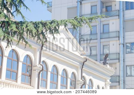 White public building with arches and multi-storey skyscraper in the city
