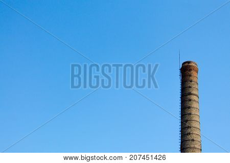 An old chimney of an old factory and against a blue sky.