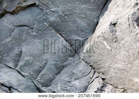 Uneven surface of gray monolithic stone with cracks