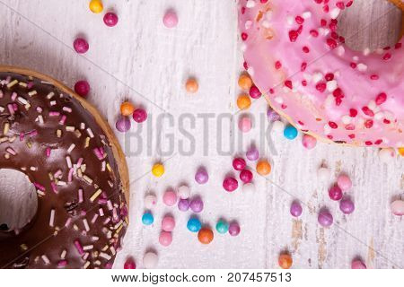 Overtop view of donuts in and sweet candy on white wooden background. Delicious junk food