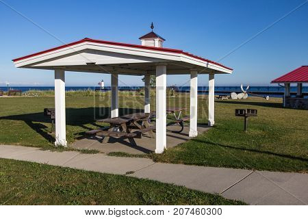 Coastal Michigan Beach Front Park. Waterfront park and picnic pavilion in the beach town of Manistee, Michigan with a lighthouse and Lake Michigan at the horizon.