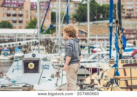 Cute Blond Boy Looking At Yachts And Sailboats