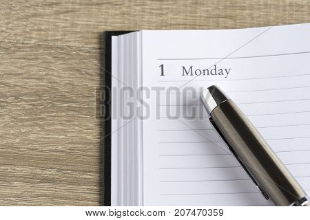 Μetal pen on a calendar with the page showing the first day of the month/week in a setting goals concept