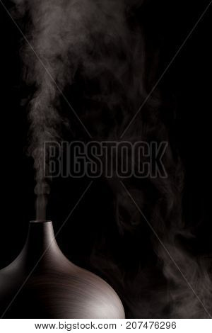 Alternative medicine. Aromatherapy essential oil diffuser device working. Close up in use against black background.