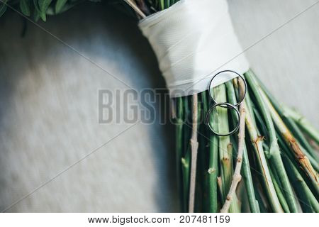 Wedding rings on a table with a bouquet of flowers
