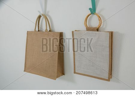 Two bags hanging on hook against white wall