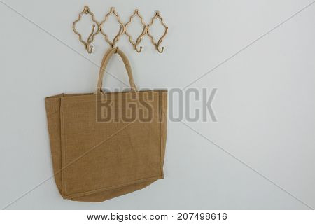 Bag hanging on hook against white wall