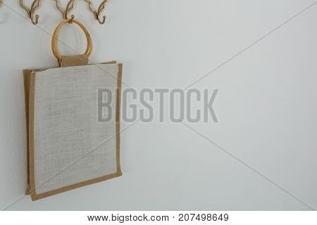 Bag hanging on hook against white wall