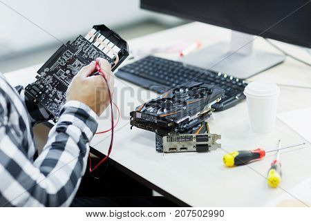 Close-up of a man who repairs a video card. Cryptocurrency. Business and finance concept.
