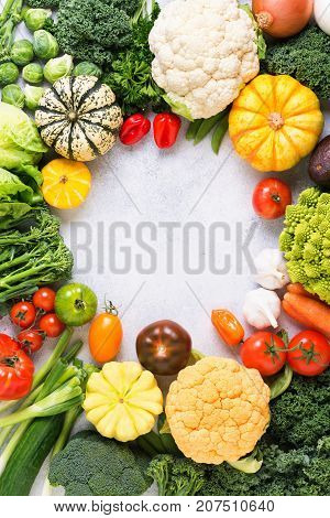 Colorful vegetables arranged in a circle frame on the light grey background, copy space for text in the middle, vertical, selective focus