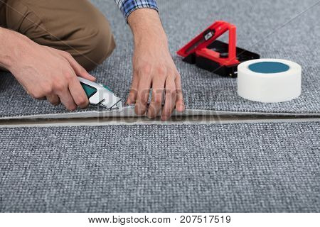 Close-up Of Carpenter Hand's Laying Carpet Using Cutter