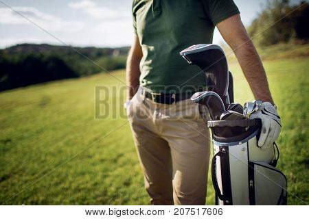 Golf Player Walking And Carrying Bag On Course During Summer Game Golfing
