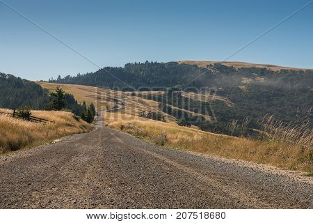 Gravel Road Snakes Through Dry Grass Hills