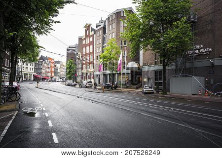 AMSTERDAM NETHERLANDS - JUNE 21 2016: Picture of the Nieuwezijds Voorburgwal Street in downtown of Amsterdam with a hotel and parked cars in a rainy day. Amsterdam Netherlands.