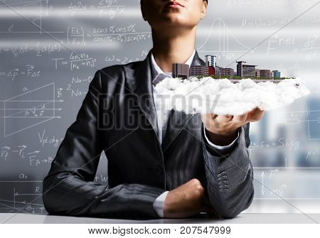Cropped image of businessman in suit presenting in his hand modern city block with office view on background. 3D rendering.