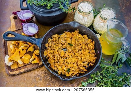 Chanterelle mushrooms with herbs on a frying pan.