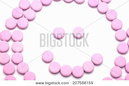 Smile face of pink pills on white background. Tablets of drug for asthma treatment