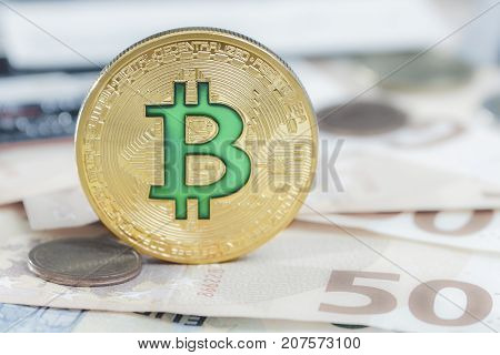 Cryptocurrency physical green bitcoin coin over the euro money.