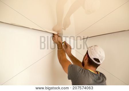 Workers stretch the stretch ceiling in the room .