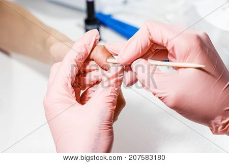 Hardware manicure in the salon. The master does a manicure to a girl, shifts the cuticle.