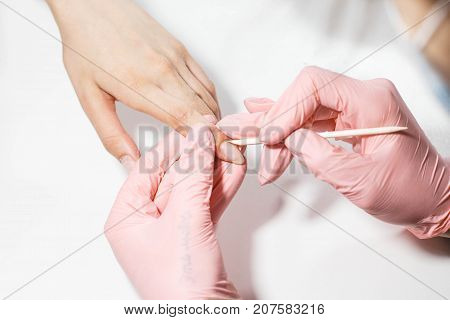 The master does a manicure to a girl. Close-up on a white background.