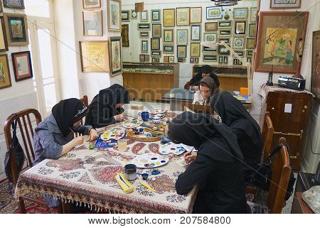 ISFAHAN, IRAN - JUNE 25, 2007: Unidentified muslim women artists in black headscarfs paint traditional Persian miniature in a workshop in Isfahan, Iran.
