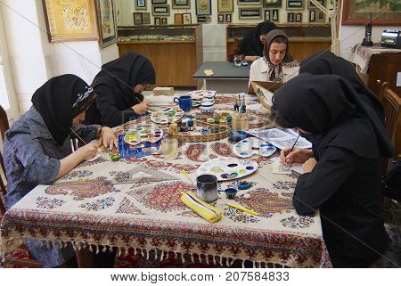 ISFAHAN, IRAN - JUNE 25, 2007: Unidentified muslim women artists in black headscarfs paint traditional Persian miniature in a workshop in Isfahan, Iran.