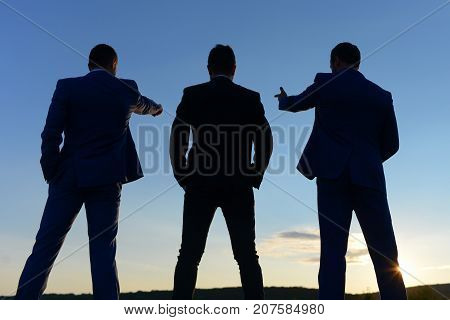 Silhouettes Of Company Leaders Standing On Sunset Sky Background.
