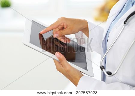 Woman doctor using tablet computer while standing straight in hospital.