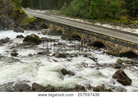 Old stone bridge crossing waterfall. Latefoss, Norway