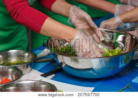 Hands of Chef mixing a vegetarian salad in stainless steel bowl