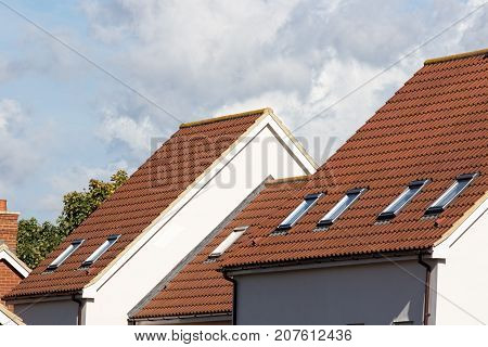 Skylight attic windows on modern clay tile roof. New residential building rooves with safety escape exit windows.