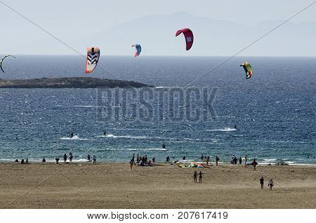 Sandy beach and the kitesurfers on the waves of the Aegean sea at Prasonisi (Greece)