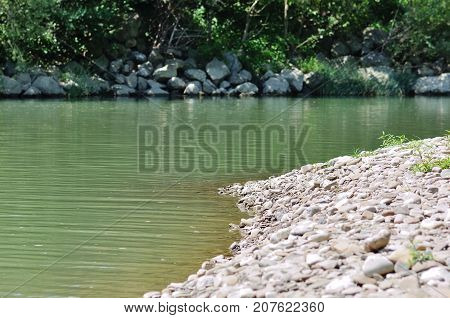 Summer landscape on a Sunny day. The river flows among small trees and flowering meadows.