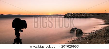 Camera on tripod with ocean and sunset in background / Podgora, Croatia