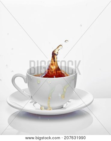Splash of tea in the cup isolated on white.