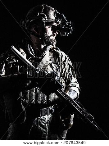 Studio contour backlight shot of special forces soldier in uniforms with weapons, portrait on black background