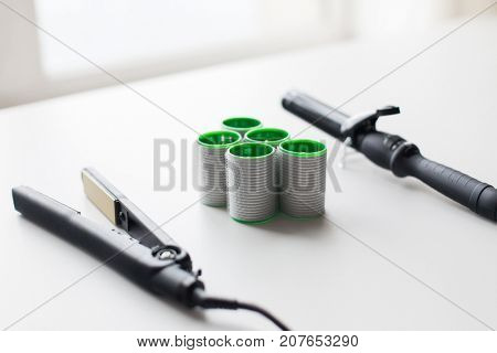 hair tools, beauty and hairdressing concept - curling iron, hot styler and curlers on white background