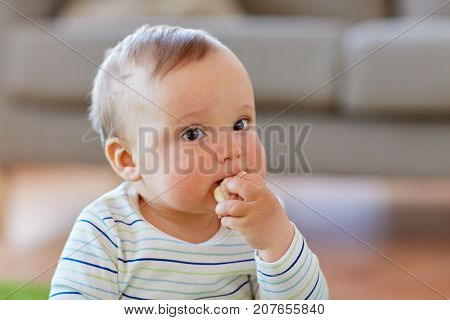 childhood, kids and people concept - baby boy eating rice cracker at home
