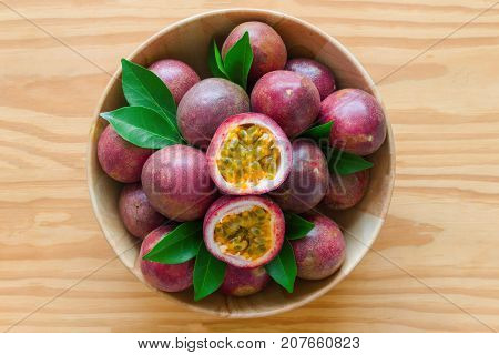Fresh passion fruit in wood bowl on wood table in top view flat lay with copy space for background or wallpaper. Ripe passion fruit so delicious sweet and sour. Passion fruit is tropical fruit.