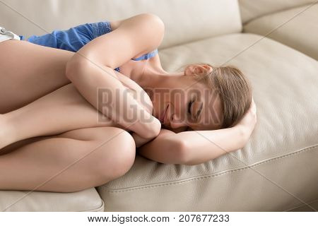 Upset depressed young woman lying on sofa, embracing her knees, adolescent girl feeling heartbroken, vulnerable teen crying at home alone, frustrated teenager having problems, suffer from loneliness