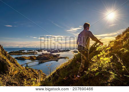 Male hiker going to the top of mount Festvagtinden with views over the village of Henningsvaer on Lofoten islands in Norway