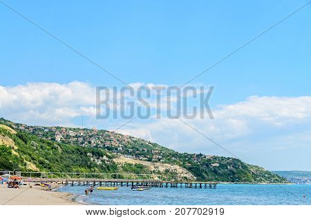 ALBENA BULGARIA - JUNE 16 2017: The Black Sea shore green hills with houses blue clouds sky. City Balchik coast.