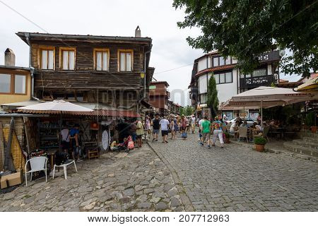 NESEBAR BULGARIA - AUGUST 21 2017: A typical residential building and a street with tourists in the old town. Nesebar is an ancient city and one of the major seaside resorts on the Bulgarian Black Sea Coast.
