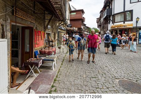 NESEBAR BULGARIA - AUGUST 21 2017: A typical residential building and a street with tourists in the old town. Nesebar is an ancient city and one of the major seaside resorts on the Bulgarian Black Sea Coast.