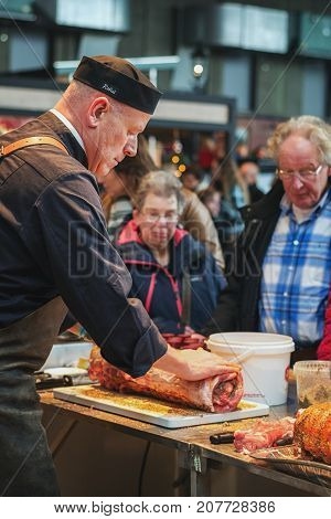Utrecht Netherlands December 9 2016: The butcher rolls a delicious piece of porc with spices at the food festival