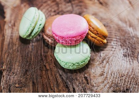 Macaroons with the flavors of coffee pistachio chocolate and raspberries presented on a piece of wood